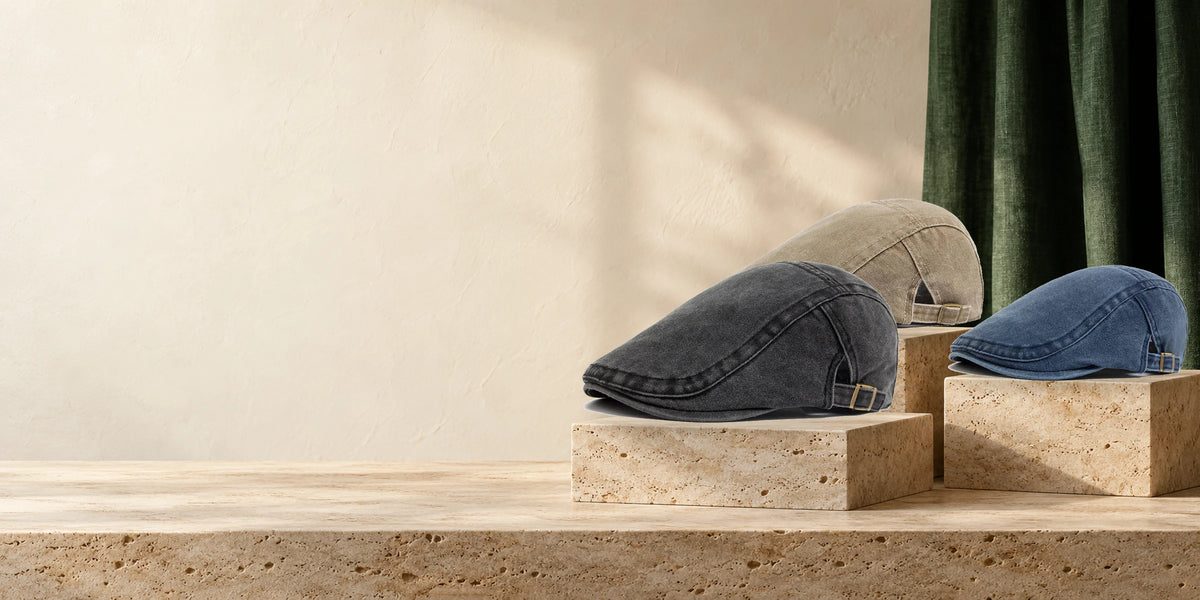 Flat caps in charcoal, beige and denim blue on stone display stands.